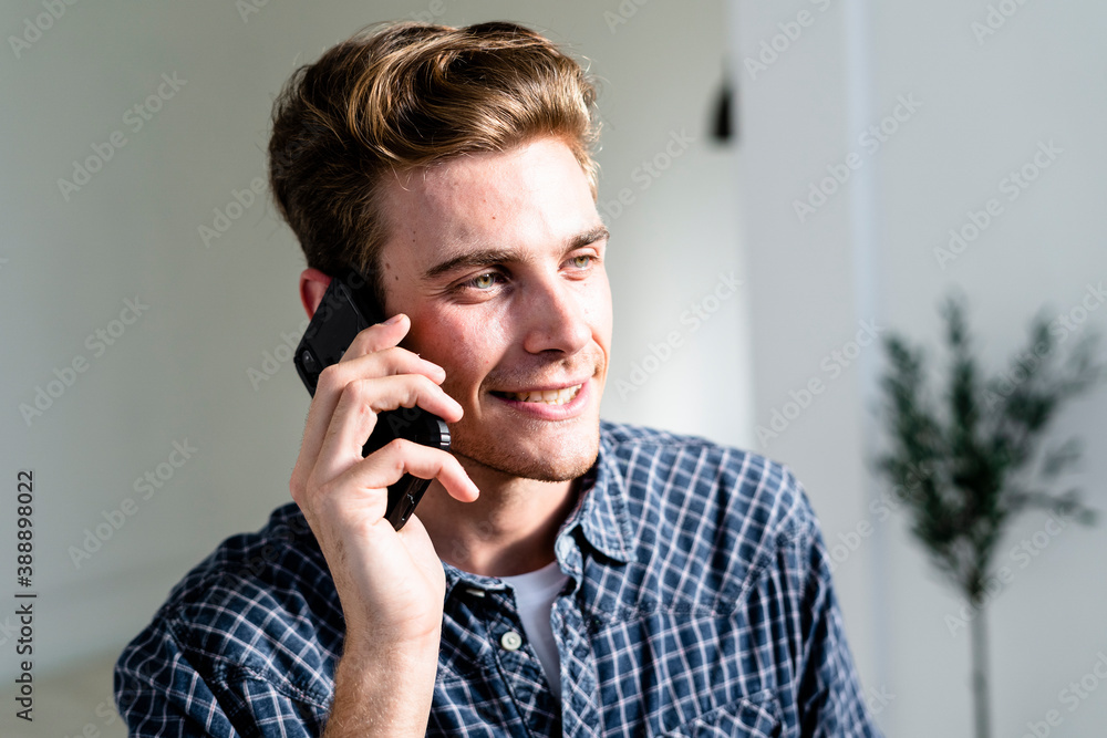 Smiling man talking on mobile phone while standing at office Smiling man talking on mobile phone while standing at office