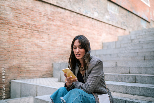 Woman using mobile phone while sitting on staircase photo