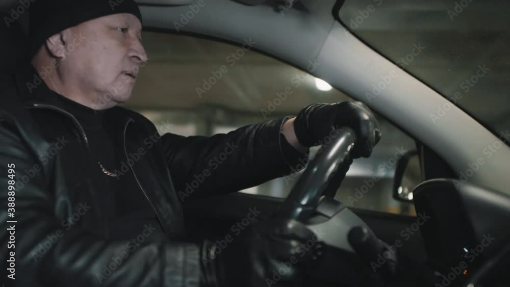 Medium close up of middle age asian gangster in black driving car escaping and then loading gun and going on deal at underground parking Medium close up of middle age asian gangster in black driving car escaping and then loading gun and going on deal at underground parking