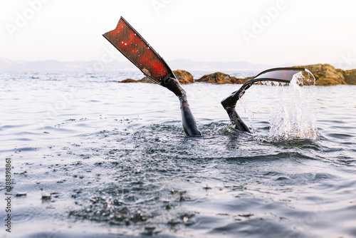 Legs of man wearing flippers diving in sea against clear sky photo