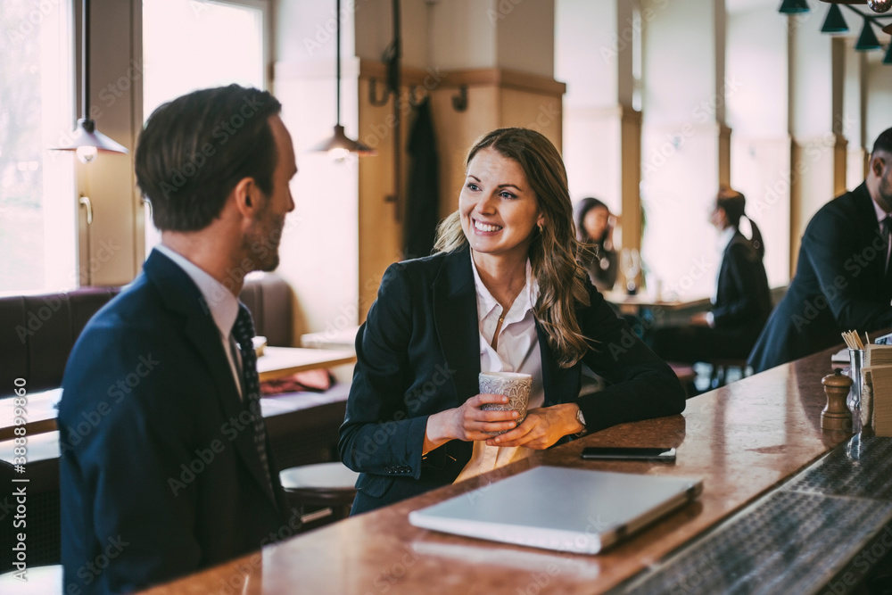 Smiling businesswoman talking to businessman in restaurant Smiling businesswoman talking to businessman in restaurant