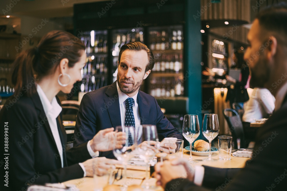 Confident businessman talking to businesswoman in restaurant Confident businessman talking to businesswoman in restaurant