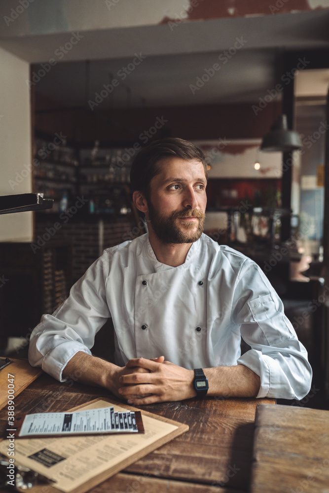 Confident chef sitting at table in restaurant Confident chef sitting at table in restaurant