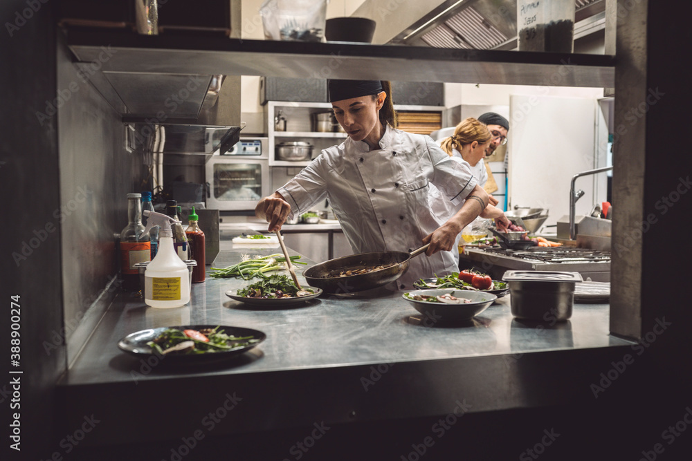 Female chef preparing food in commercial kitchen Female chef preparing food in commercial kitchen
