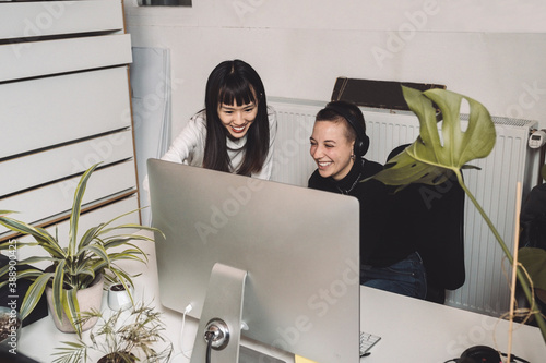 Smiling entrepreneurs working on computer at place of work photo