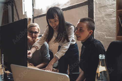 Smiling entrepreneur discussing with coworkers at workplace photo