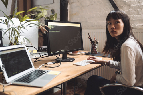 Businesswoman looking away while working on computer at workplace photo