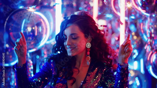 Joyful woman dancing with bengal lights in club. Girl having fun in nightclub