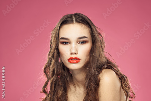 Attractive woman fashionable hairstyle bared shoulders and red lips pink background