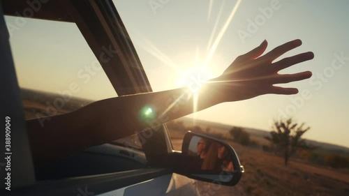 free girl hand out of the window rides a car wind in the face. concept car travel on the road. girl stretches her hand out of the car window sun glare sunset. driver hand out of the window movement photo