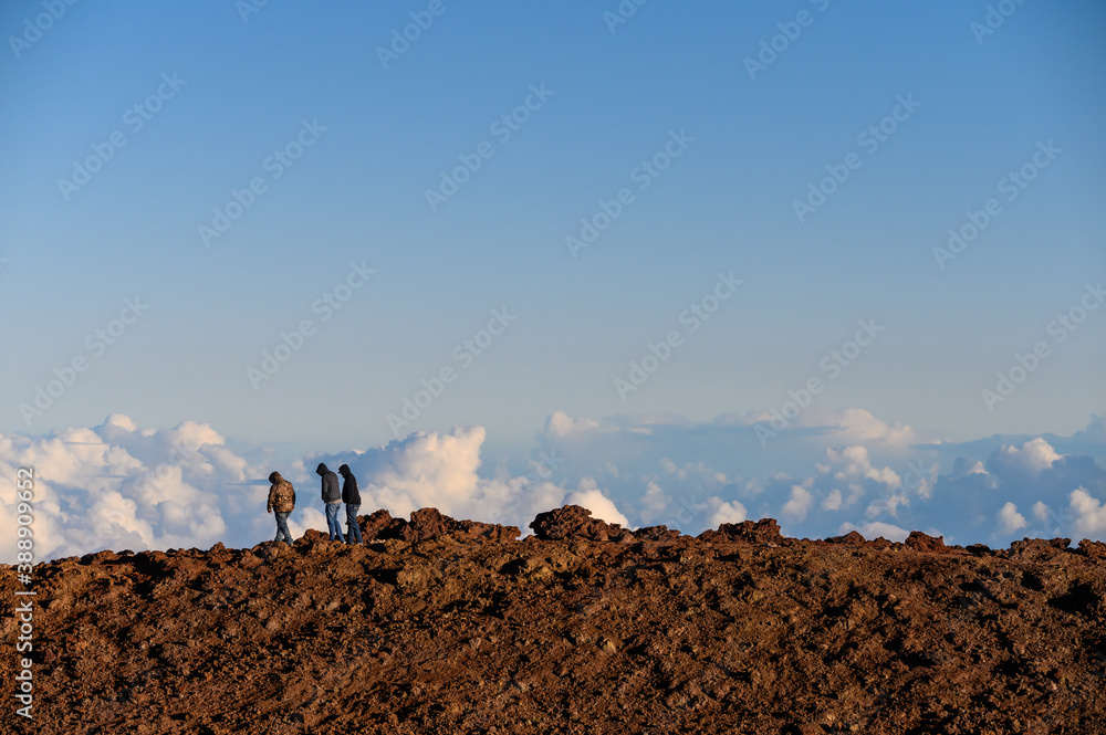 HAWAII / USA - APRIL 10 2019: Friends walking over rocks on Haleakala National Park with clouds in the background.