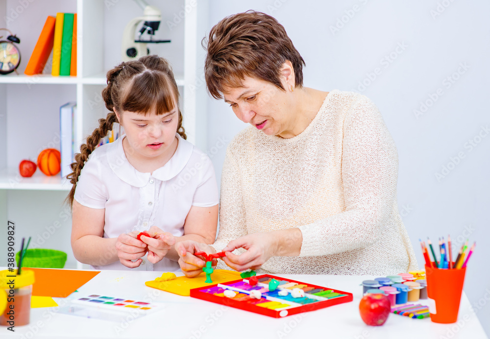 The teacher shows the student with down syndrome how to do creativity ...