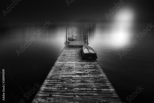 Black and white photography of the wooden bridge leading into the distance on the lake