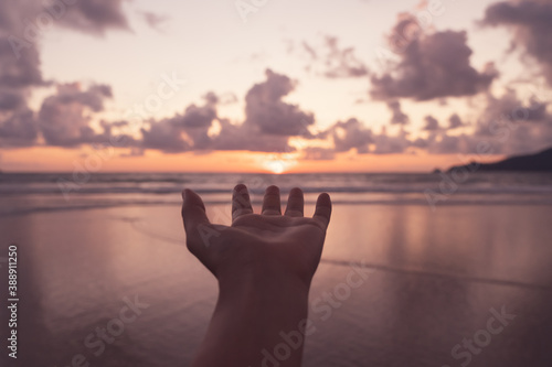Woman hand reach out to sunset beach.