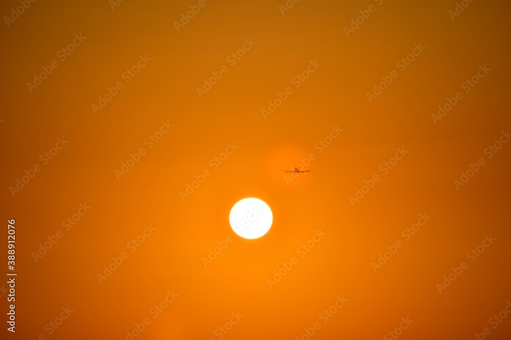The plane is gaining altitude, with evenly spread wings. Flies in orange sunset in the spot of reflection. The plane is gaining altitude, with evenly spread wings. Flies in orange sunset in the spot of reflection.