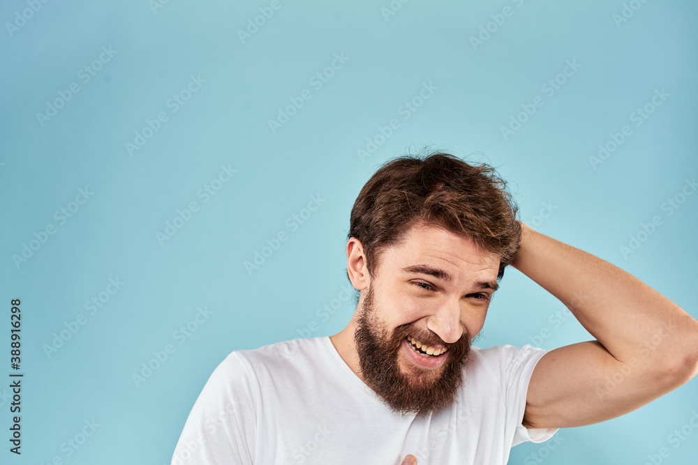 Emotional man with a beard in a white t-shirt blue background fun lifestyle Emotional man with a beard in a white t-shirt blue background fun lifestyle