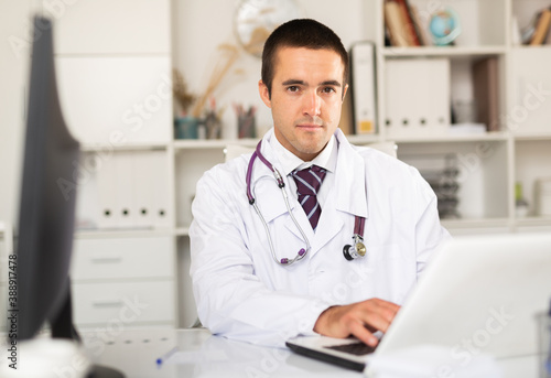 Cheerful man doctor working effectively in her office