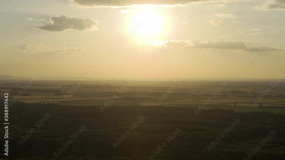 Golden hour sunset shot of vast hazy farmland on horizon from high overlook view Golden hour sunset shot of vast hazy farmland on horizon from high overlook view