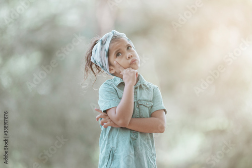 Latin young girl looking away with a thoughtful expression in a countryside. Childhood and education concept.
