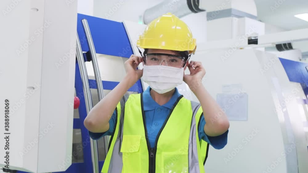 Asian woman worker put on protective face mask in production factory. Asian woman worker put on protective face mask in production factory.