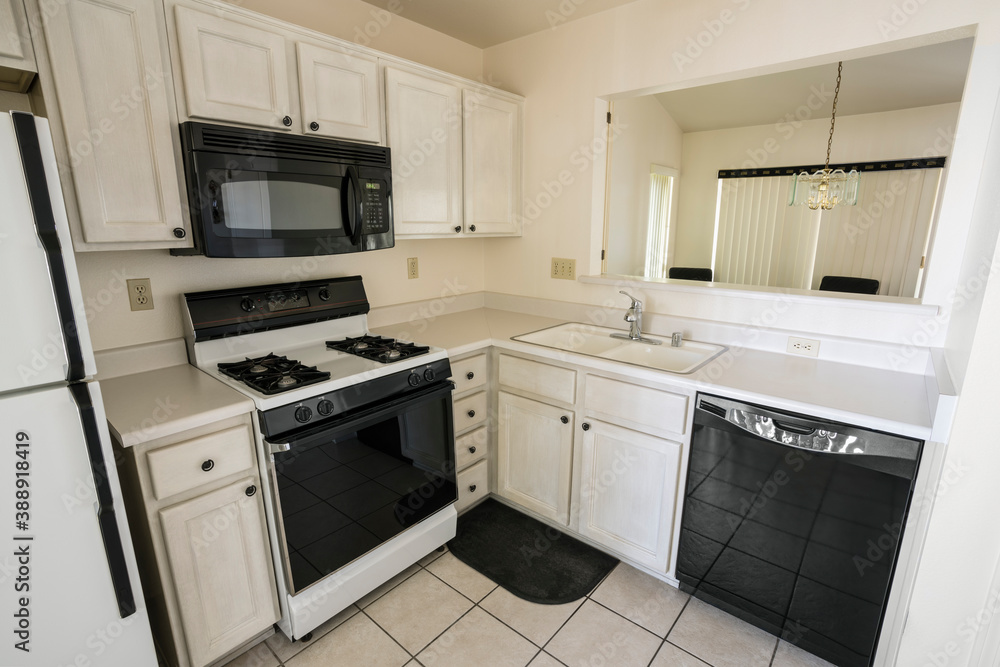 Clean 1990s style suburban condo kitchen with light colored cabinets and tile floor. Clean 1990s style suburban condo kitchen with light colored cabinets and tile floor.