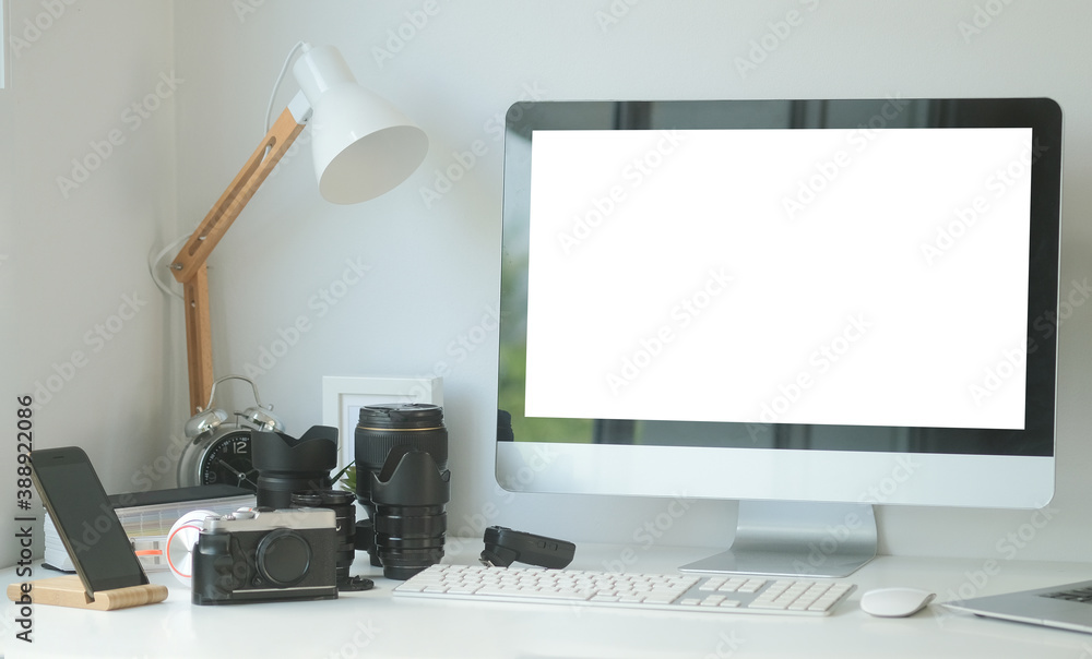 Fototapeta premium Mock up computer with white screen and medium format camera on designer or photographer table. Photographer or designer workspace.