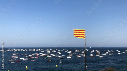 Slow motion shot of Calella de Palafrugell in Costa Brava, Spain. View of some fishermen boats in the sea and the catalan flag waving in the wind. photo