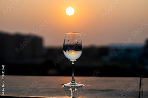 Clear liquid being poured into a wine glass at sunset