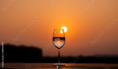 Clear liquid being poured into a wine glass at sunset