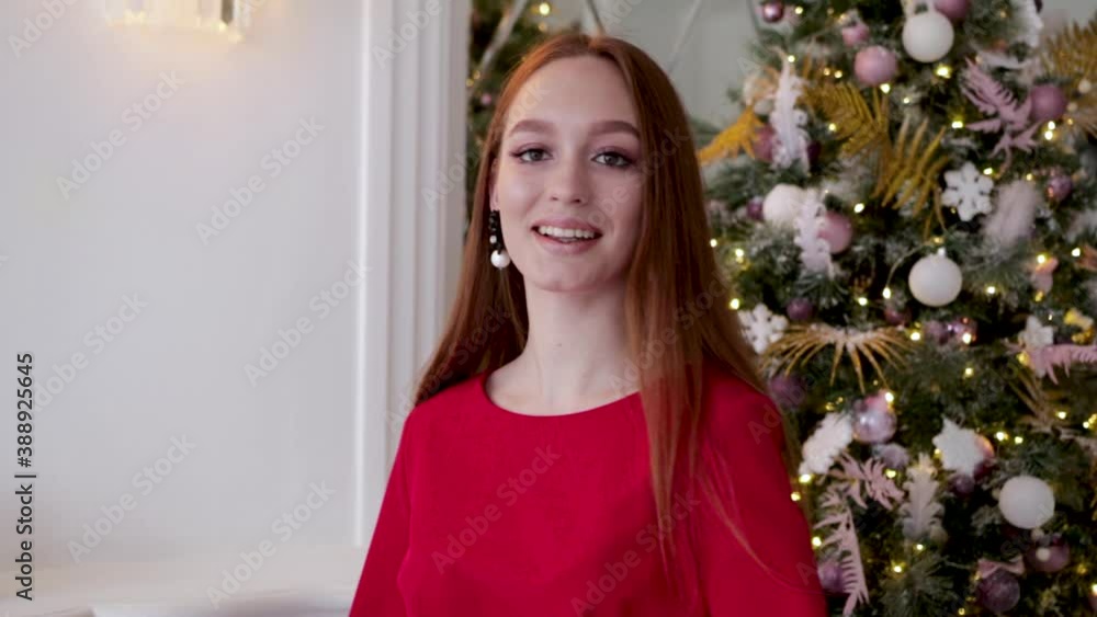 A girl in a red dress is walking near the Christmas tree at home. Beautiful sexy girl next to the Christmas tree. Brunette posing next to a Christmas tree. Girl chooses a gift for a Christmas tree A girl in a red dress is walking near the Christmas tree at home. Beautiful sexy girl next to the Christmas tree. Brunette posing next to a Christmas tree. Girl chooses a gift for a Christmas tree