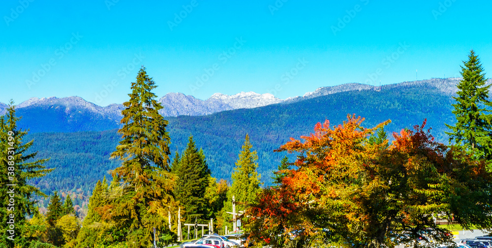 Warm Fall colors on a bright, sunny day at a popular BC public park, with snow-dusted mountain backdrop