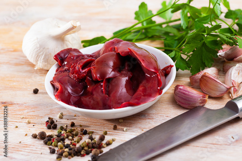 Image of raw rabbit liver with garlic and greens during cooking