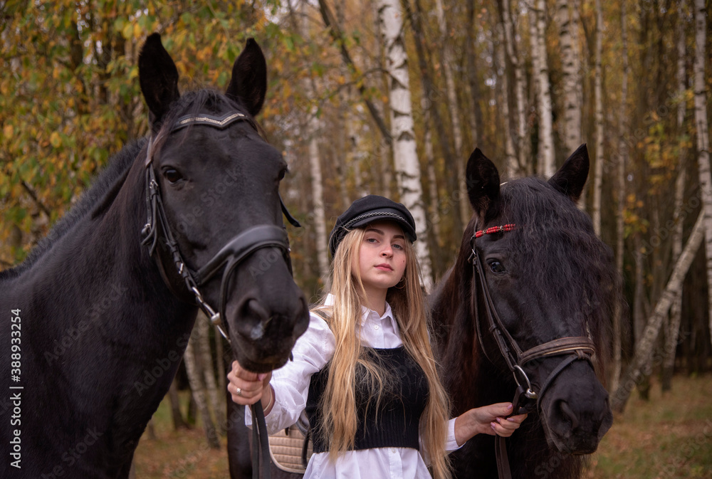 Obraz premium A young slender girl with blonde hair leads two horses .