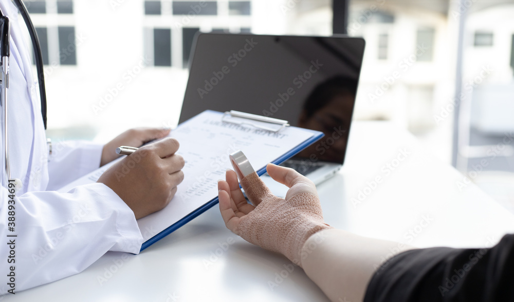 Doctor is examining a patient who has a finger splint in the examination room. Doctor is examining a patient who has a finger splint in the examination room.