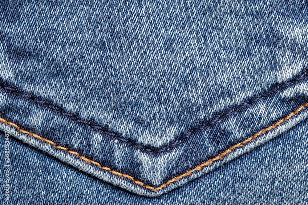 Denim background texture. Close-up of details of a light blue jeans fabric jean surface with gold and blue colored double seam. Macro. Top view. Beautiful backdrop with space. Denim background texture. Close-up of details of a light blue jeans fabric jean surface with gold and blue colored double seam. Macro. Top view. Beautiful backdrop with space.