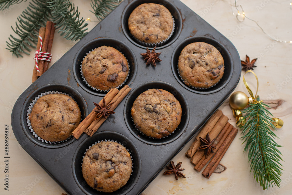 Fresh homemade gingerbread muffins in baking form on wooden table with Christmas decoration