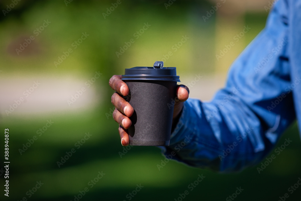 Close up of black man hand holding a cup of coffee in a park Close up of black man hand holding a cup of coffee in a park
