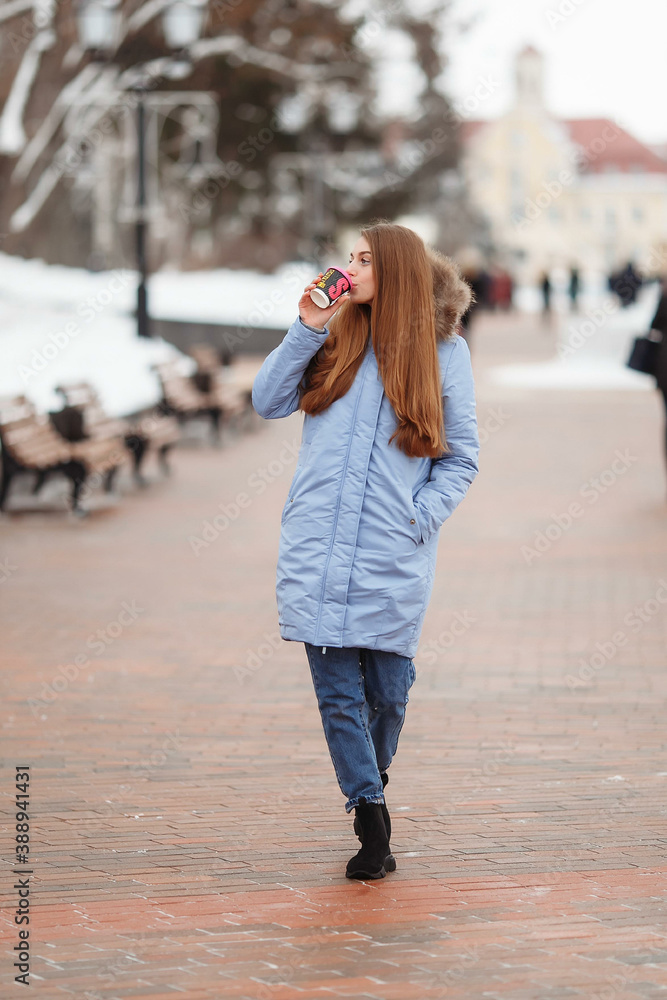 young woman walks in a winter park with coffee. winter park in the snow