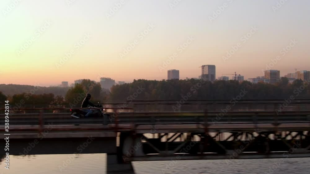 Aerial Picture of Biker Speed Riding Motorcycle in Evening Road. Cinematic Shot of Motorbike on Sunset Way on Bridge. Birds View on Motorcyclist in Driving along River. Conception Freedom Lifestyle Aerial Picture of Biker Speed Riding Motorcycle in Evening Road. Cinematic Shot of Motorbike on Sunset Way on Bridge. Birds View on Motorcyclist in Driving along River. Conception Freedom Lifestyle