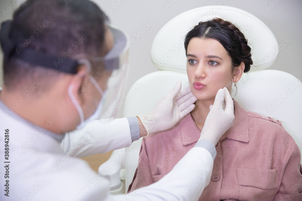 Young pretty woman in beauty salon consults with beautician on anti-aging treatments. Doctor points on fine lines and wrinkles on patient's face Young pretty woman in beauty salon consults with beautician on anti-aging treatments. Doctor points on fine lines and wrinkles on patient's face