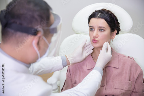 Young pretty woman in beauty salon consults with beautician on anti-aging treatments. Doctor points on fine lines and wrinkles on patient s face