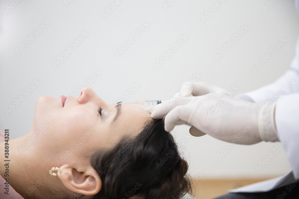 Fototapeta premium Young woman getting beauty facial injections in salon. Beautician makes cosmetic injection into the patient frown lines. Beauty injections, mesotherapy, revitalization and rejuvenation