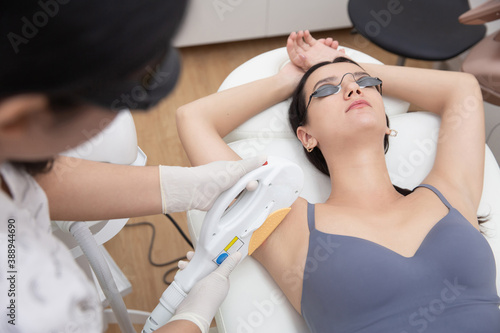 Young woman getting underarm laser hair removal epilation. IPL treatment in cosmetic beauty salon