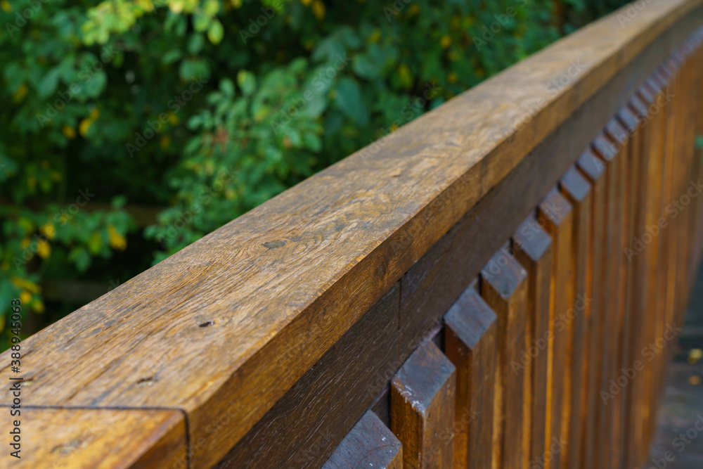 Wooden railing of the bridge. The greenery in the background is out of focus. Close-up. Wooden railing of the bridge. The greenery in the background is out of focus. Close-up.