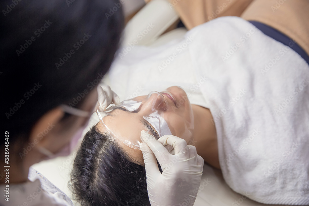 Cosmetologist or beautician applies a hydrogel collagen mask to client face in beauty salon. Healthcare, wellness and medicine Cosmetologist or beautician applies a hydrogel collagen mask to client face in beauty salon. Healthcare, wellness and medicine