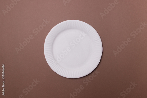 white eco-friendly paper plate on brown colored paper background. top view. mock-up