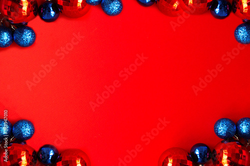 Multicolored red and blue Christmas balls on bright red background. Merry Christmas card. Concept of celebrating new year