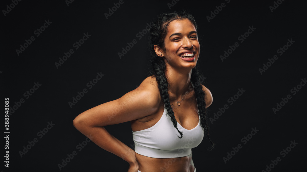 Smiling fit woman on black background - obrazy, fototapety, plakaty 