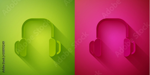 Paper cut Winter headphones icon isolated on green and pink background. Earmuffs sign. Paper art style. Vector.