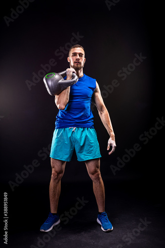A man in a blue T-shirt and shorts trains with a kettlebell.
